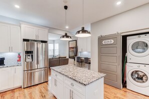 Una cocina moderna con electrodomésticos de acero inoxidable, una isla con encimera de granito y lavadora y secadora integradas.