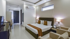 A hotel room with a bed, bedside tables, a desk, and a chair. - Royal Residence Golf View (Gurugram)
