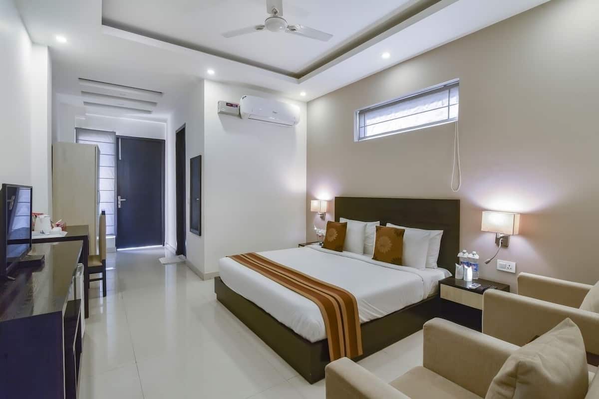 A hotel room with a bed, bedside tables, a desk, and a chair.
