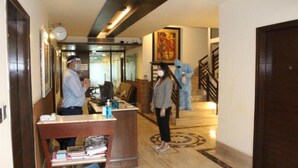 A hotel lobby with a reception desk, a clock, a staircase, and a painting on the wall. - Royal Residence Golf View (Gurugram)