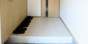 A wooden floor with a white bench and a row of black slippers. - Sakura 93 (Sapporo)