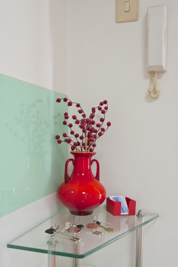 A glass table with a red vase containing red berries, a set of keys, and a red box. - port view center city (Split)