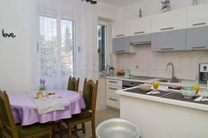 A kitchen with a dining table set for two, a sink, and a countertop with various items.
