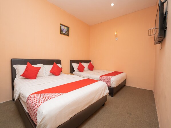 A hotel room with two beds, each with white bedding and red pillows, and a small painting on the wall.