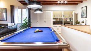 A pool table with a blue felt surface, surrounded by wooden cabinets and a bookshelf filled with books. - Urdaibai by Interhome (Urdaibai/Busturia)