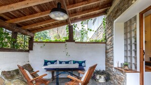 An outdoor patio with a stone wall, wooden ceiling, and a table with chairs. - Urdaibai by Interhome (Urdaibai/Busturia)