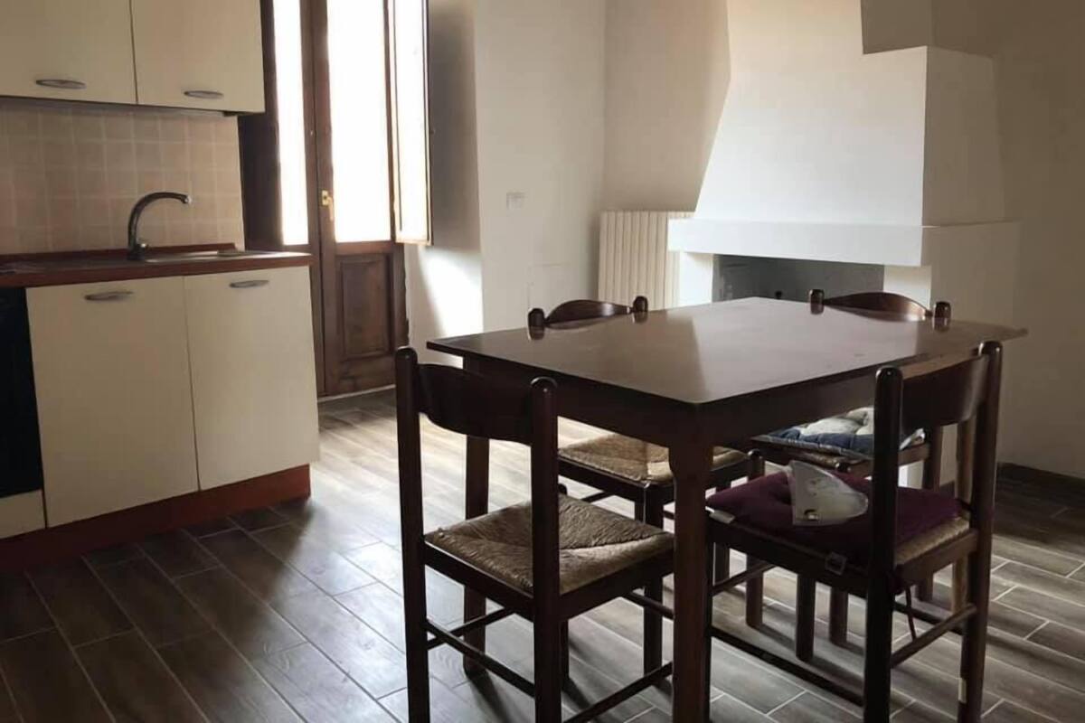 Una cocina con una mesa de comedor, sillas, un fregadero y armarios.