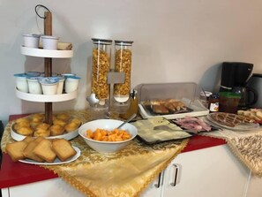 A buffet table with various food items including pastries, sandwiches, and a bowl of fruit. - Il Minotauro (Vittorito)