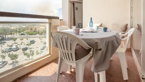Un balcón con una mesa lista para dos personas, sillas y vista a un estacionamiento y edificios.