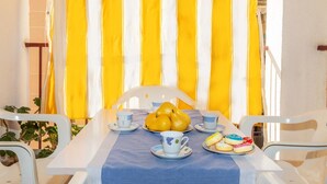 Una mesa de comedor decorada con cortinas a rayas amarillas y blancas, una silla blanca y una servilleta de mesa azul.