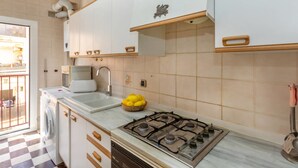Una cocina con estufa a gas, un lavamanos y una lavadora.