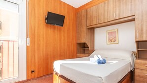 Habitación de hotel con cama, armario de madera, televisor montado y un cuadro en la pared.