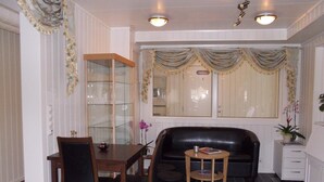 A room with a dining table, chairs, a sofa, a small side table, and a cabinet. - Håkon Gjestehus (Kåfjord)