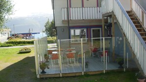 A two-story building with a balcony area featuring outdoor seating. - Håkon Gjestehus (Kåfjord)