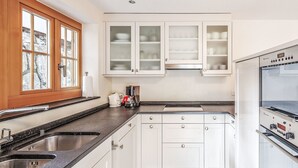 A kitchen with white cabinets, a double sink, a coffee maker, and a built-in oven.