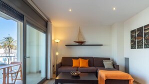 A modern living room with a sofa, coffee table, and a dining area with a table and chairs. - Del Port by Interhome (Empuriabrava)