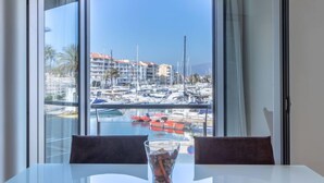 A dining area with a view of a marina, a glass table, and two chairs. - Del Port by Interhome (Empuriabrava)