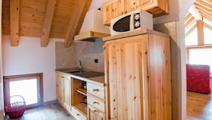 A wooden kitchen with a microwave, sink, and cabinets. - Albergo Diffuso - Cjasa de Barce by Interhome (Barcis Lake)