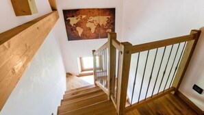 A wooden staircase with a metal railing, white walls, and a world map on the wall. - Albergo Diffuso - Cjasa de Barce by Interhome (Barcis Lake)