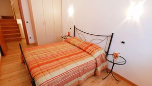 A bedroom with a bed, wooden flooring, a nightstand, and a wall-mounted light fixture. - Albergo Diffuso - Cjasa Marisa by Interhome (Barcis Lake)