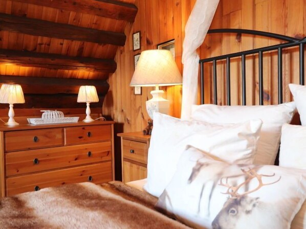 Ein gemütlicher Holzraum mit einem Bett, zwei Nachttischen mit Lampen und einem Holz-Kopfteil.