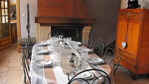 Un comedor con una mesa larga dispuesta para seis comensales, una chimenea y un armario de madera.