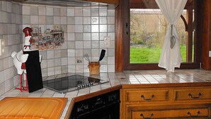 Una cocina con salpicadero de azulejos, estufa, lavavajillas y una ventana con cortinas.