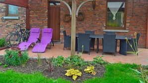 Una casa de ladrillo con un patio que incluye sillones morados, una mesa y sillas.