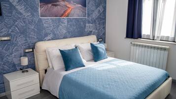 Une chambre à coucher avec un lit, une table de chevet, une lampe et un tableau accroché au mur.
