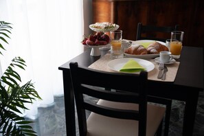 A breakfast setting with a plate of croissants, a bowl of fruit, and two glasses of orange juice on a table. - Casa del Marchese B&B (Riposto)