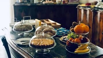 Une table de buffet proposant divers plats, notamment des pâtisseries, des fruits et un gâteau.