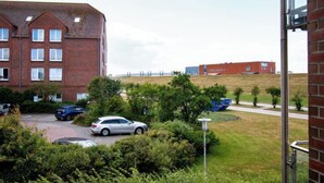 Un edificio residencial con varias ventanas y un estacionamiento con coches.
