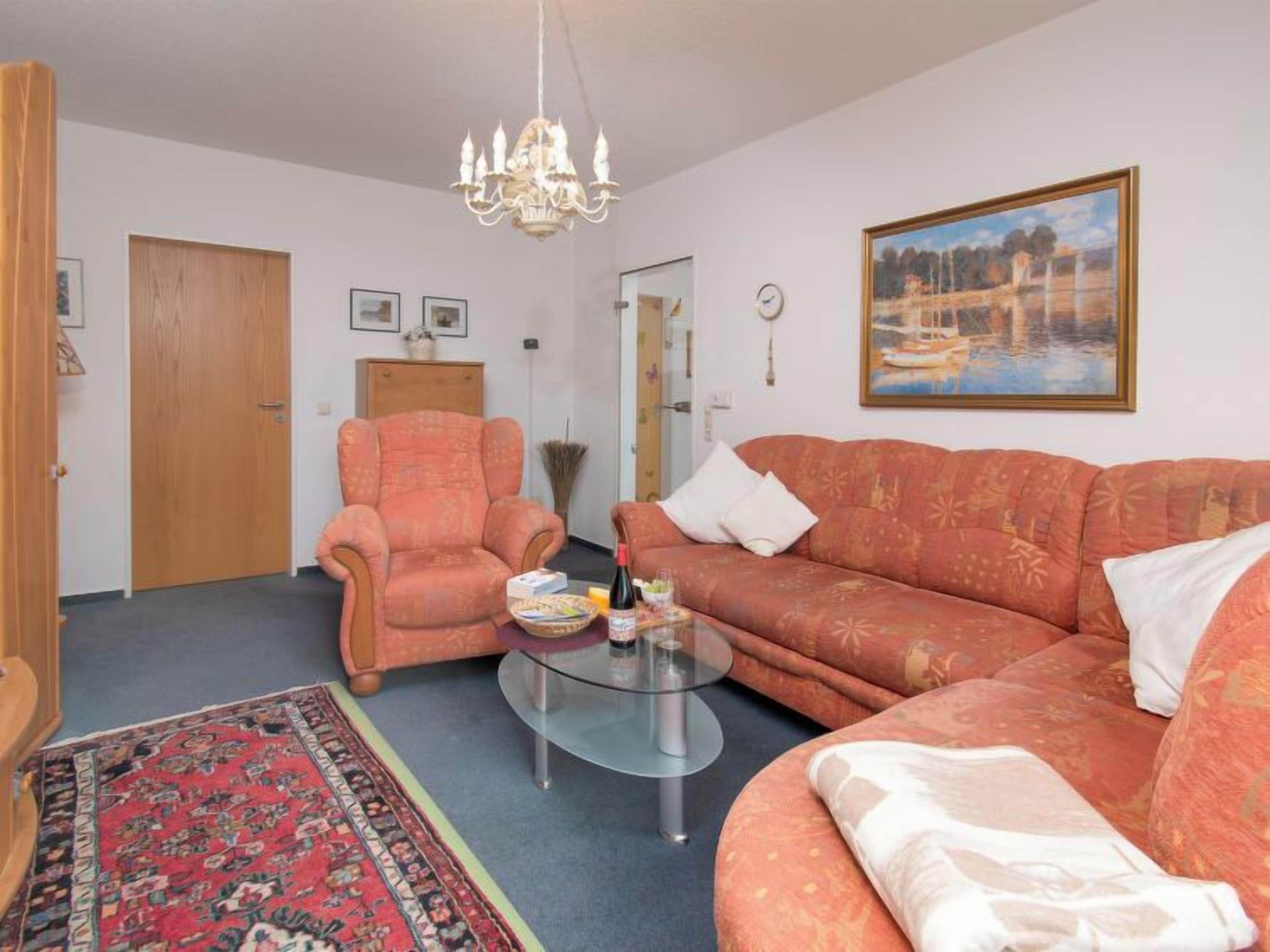A living room with a sofa, armchair, and a glass coffee table.