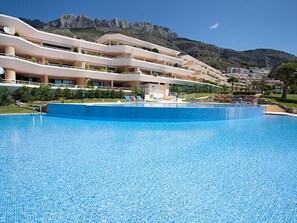 Un hôtel doté d’une grande piscine, de nombreux balcons et offrant une vue sur un paysage montagneux.