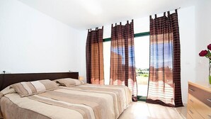 Une chambre à coucher avec un lit, des rideaux, une commode et un vase de fleurs.