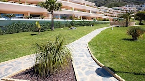 Un hotel moderno con diversi piani, un cortile centrale con una palma e montagne sullo sfondo.