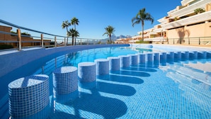 Una piscina con gradini piastrellati di colore blu, palme e cielo sereno.
