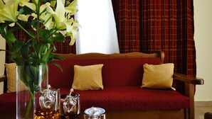 A room with a wooden table, a vase with flowers, and a red sofa with cushions. - Verga Apartments & Suites (Kalamata)