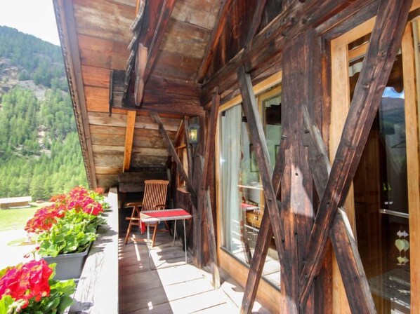 A wooden cabin with a porch, a table, and chairs. - Beim Holzschnitzer by Interhome (Sölden)