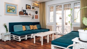 Un salón moderno con un sofá color turquesa, una mesa de centro blanca y suelo de madera.