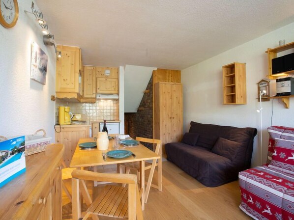 Ein gemütlicher Wohnbereich mit Esstisch aus Holz, einer Couch und einer Küchenzeile.