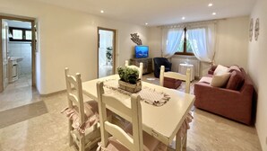 A dining area with a table and chairs, a sofa, a television, and a window with curtains. - Stefano by Interhome (Forte dei Marmi)