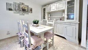 A dining area with a white table and chairs, a potted plant, and a wall-mounted artwork. - Stefano by Interhome (Forte dei Marmi)