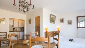 Une chambre d’hôtel confortable avec un coin repas, un lit avec une literie blanche et un lustre.
