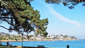 Un parc côtier doté d’une pelouse, de bancs et offrant une vue sur la mer et les bateaux.