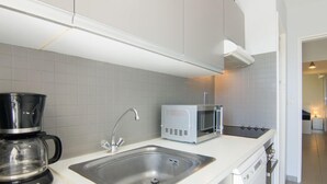 Een moderne keuken met een roestvrijstalen spoelbak, een koffiezetapparaat en een magnetron.