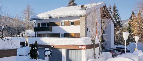 A modern multi-story building with a snow-covered roof and a garage door.