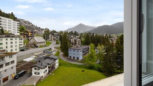A residential area with a mix of modern and traditional buildings, a road, and a mountain in the background. - Allod Park Haus C 701 by Interhome (Davos)