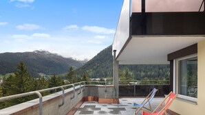A balcony with a view of mountains, a railing, and two folding chairs. - Allod Park Haus C 701 by Interhome (Davos)