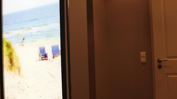 A hallway with a view of a beach through a glass door. - Altstadt Villa Wohnung 3 Memmert (Borkum)